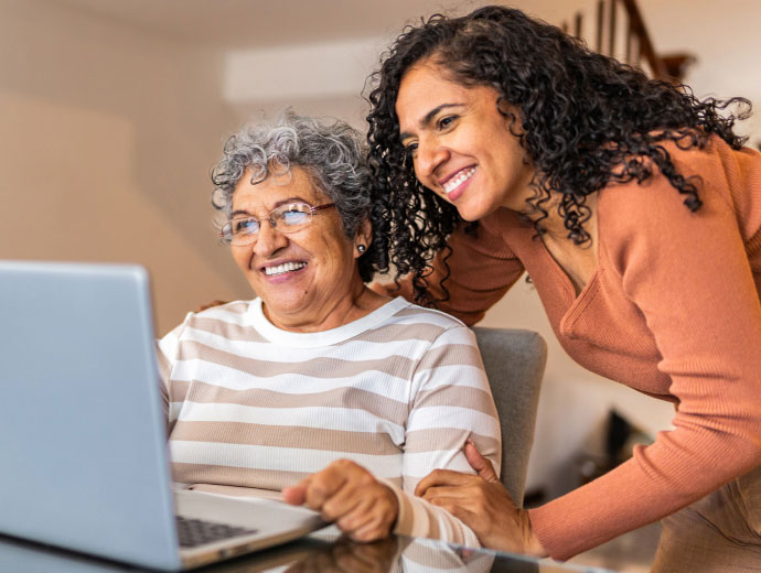 adult woman helping an older woman with a laptop